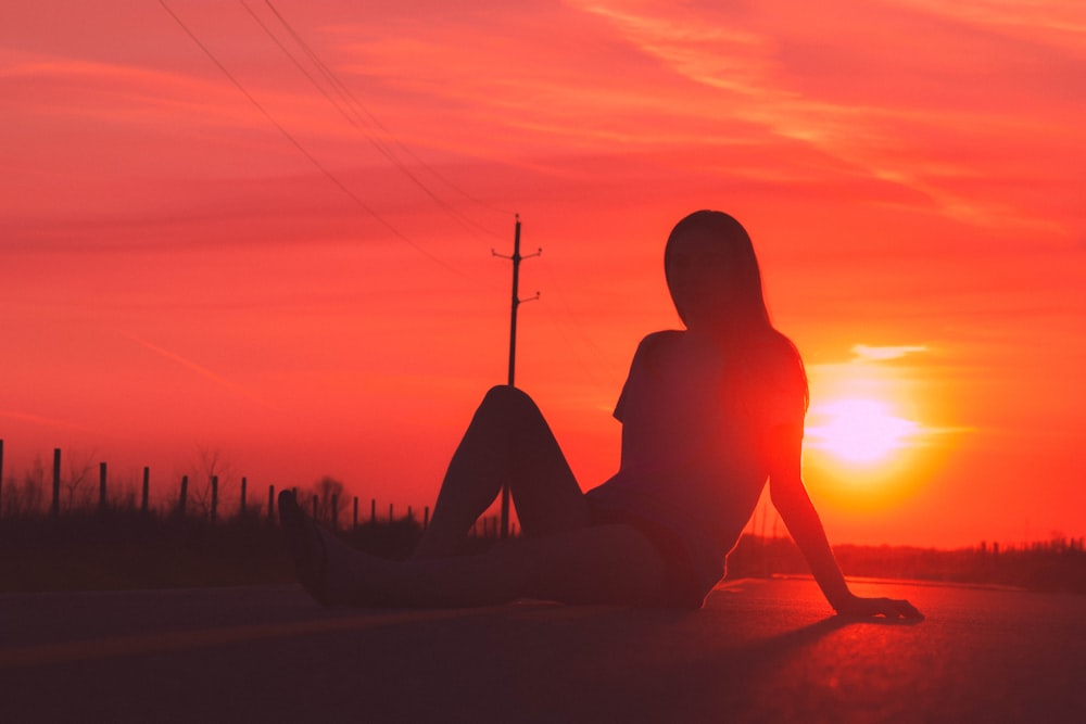 silhouette of woman sitting in road during golden hour