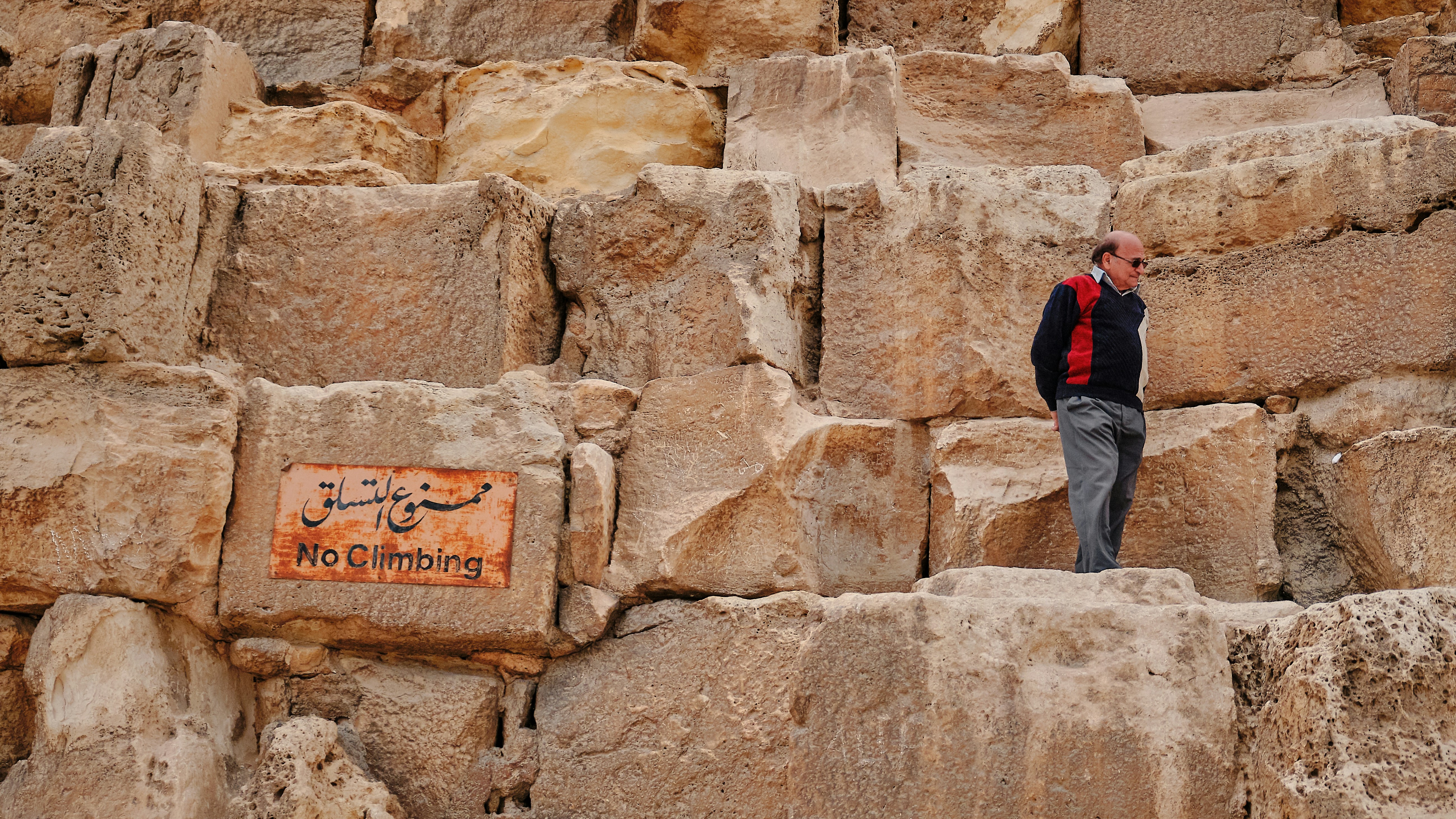 Man in red and black sweater standing near cliff