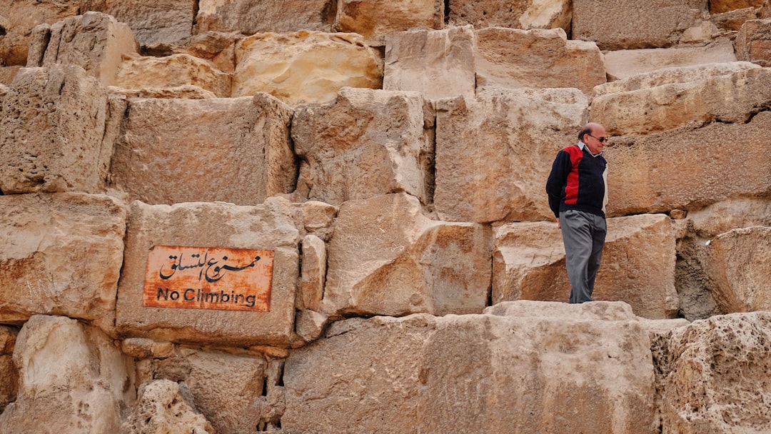 man in red and black sweater standing near cliff