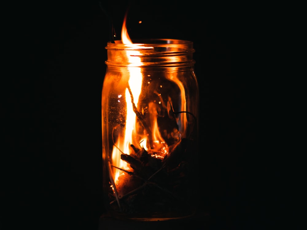 a fire in a glass jar with a black background