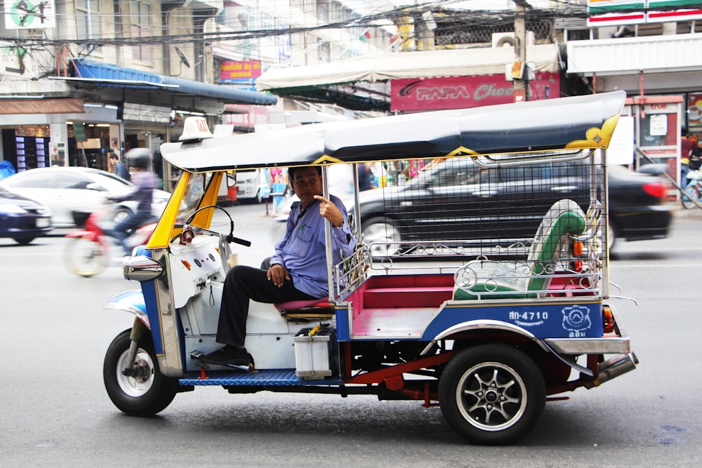 man driving multicolored 3-wheel vehicle