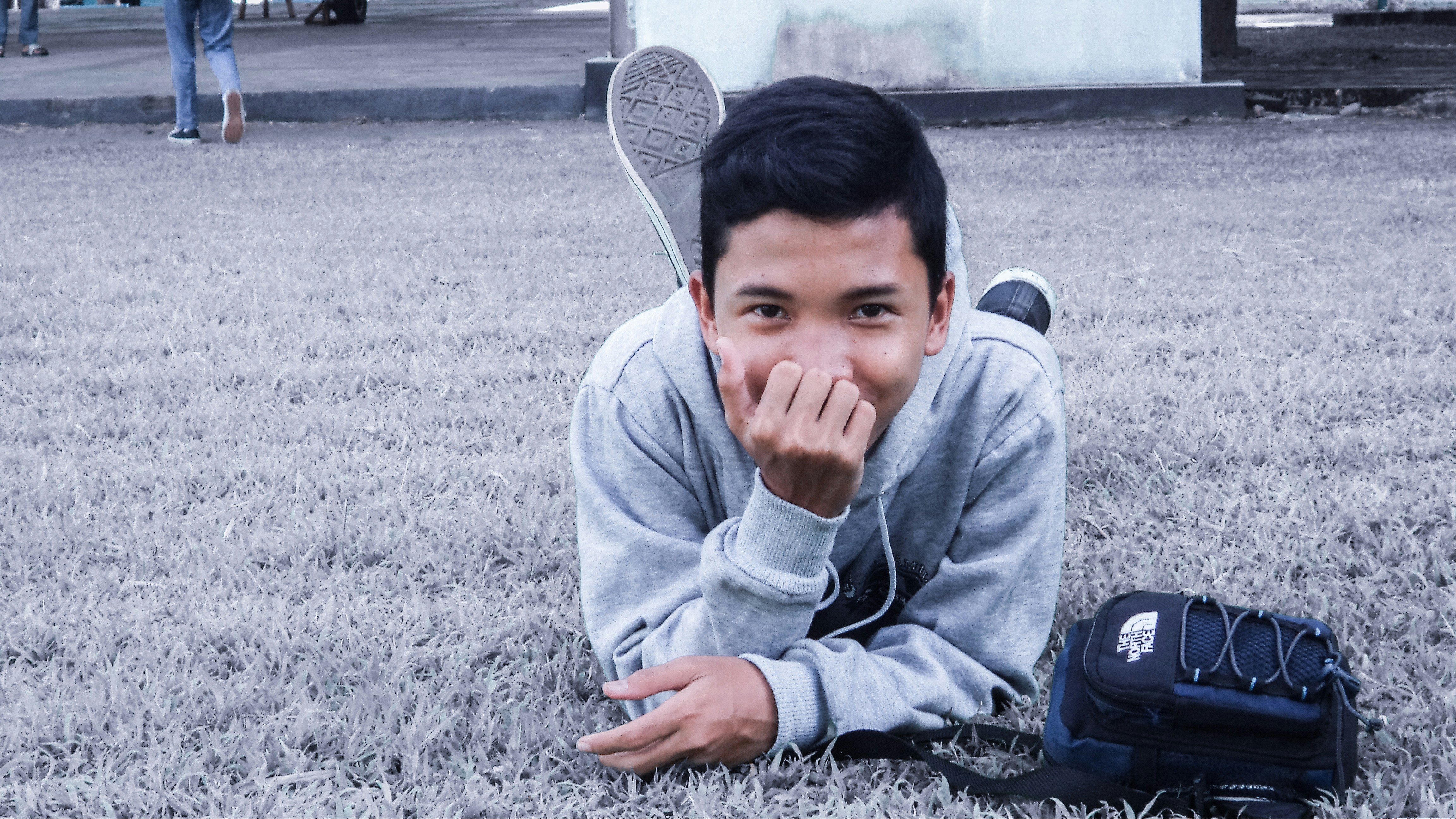 man lying on field grayscale photo
