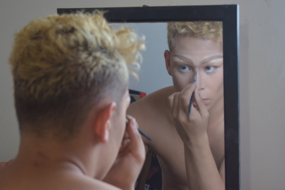 man holding black stick applying makeup