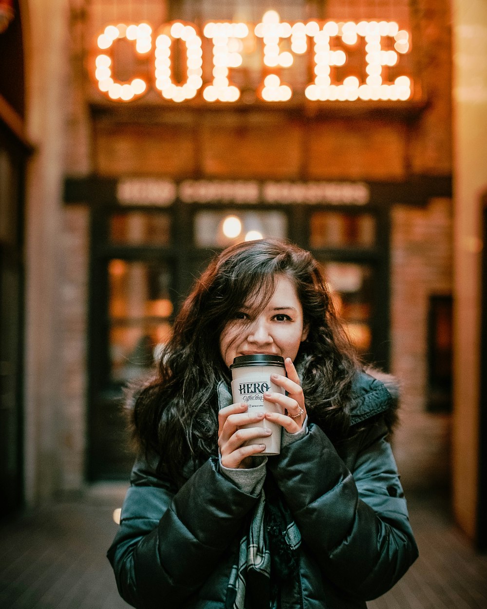 woman holding hot beverage outside coffee shop