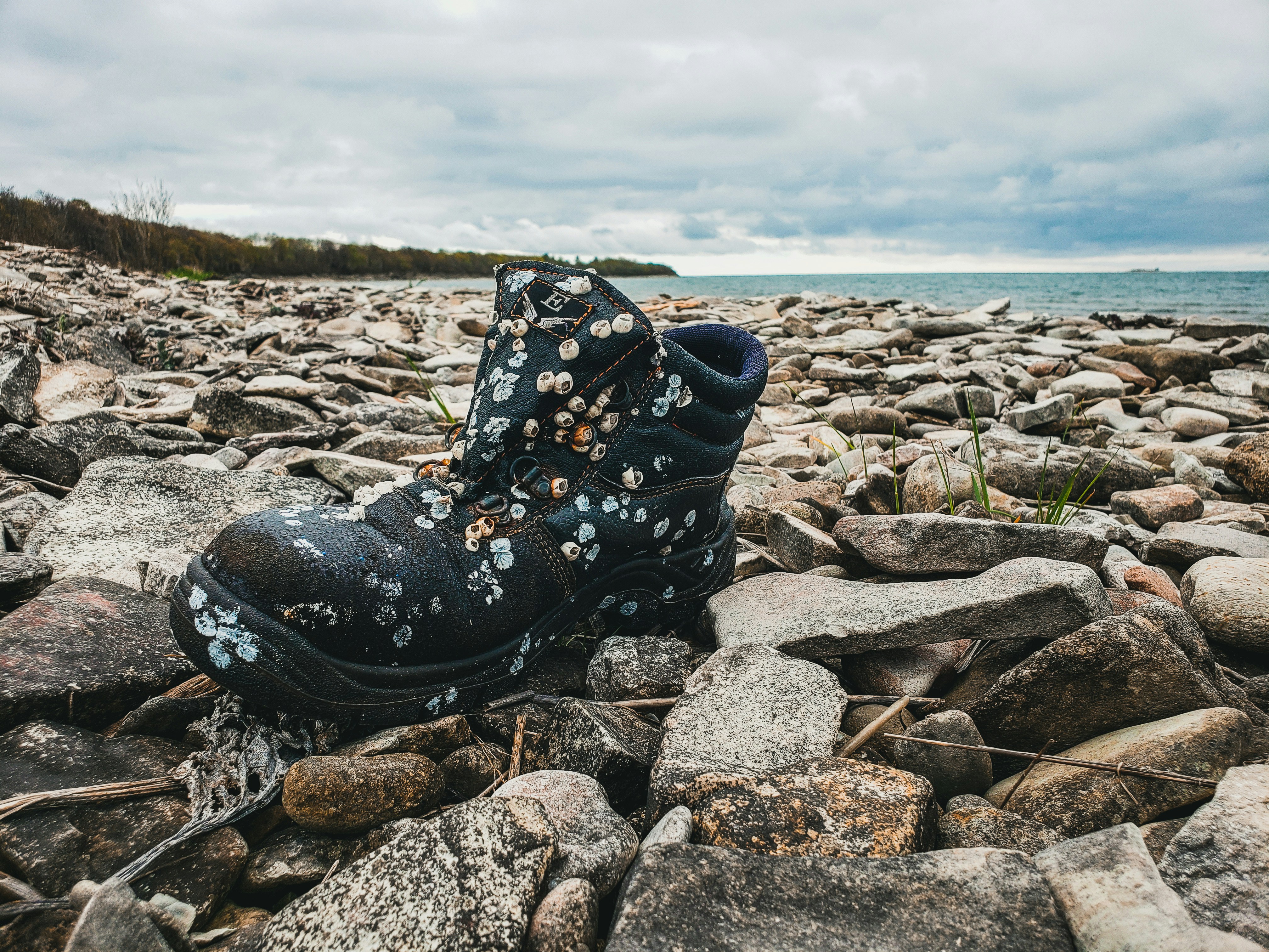 unpaired black boot on rocks