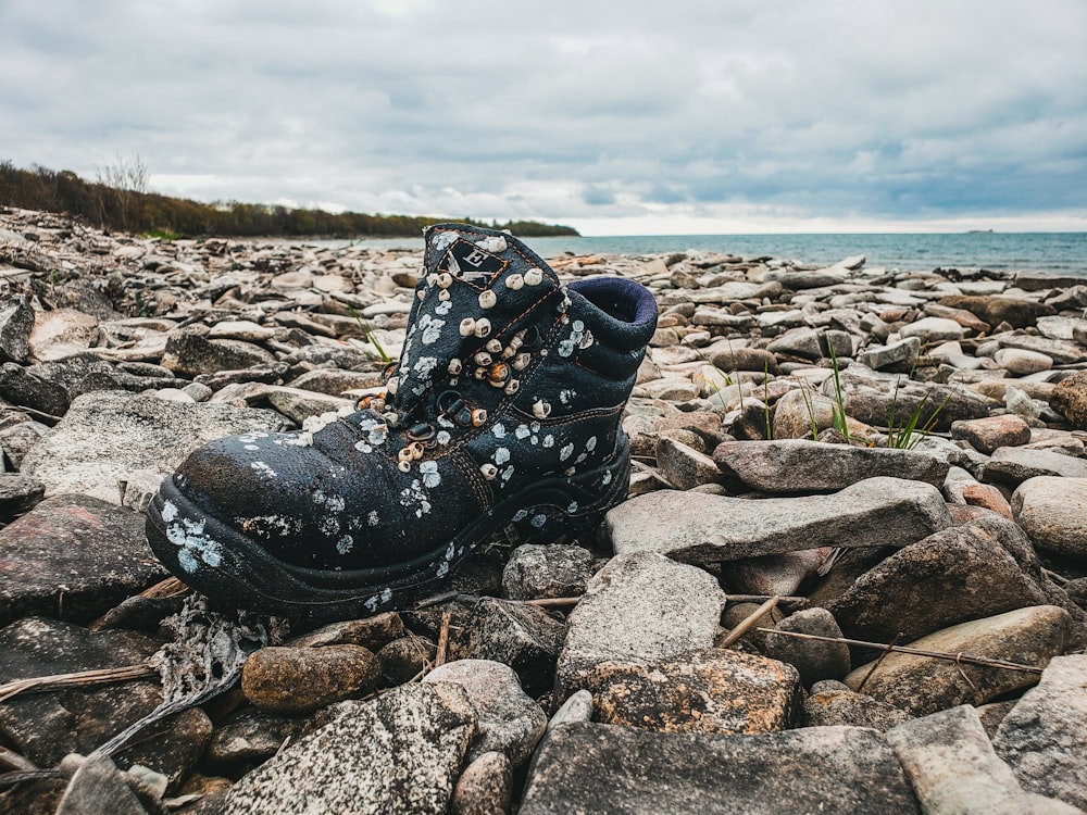 unpaired black boot on rocks