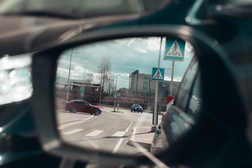 vehicle side mirror viewing red vehicle on road