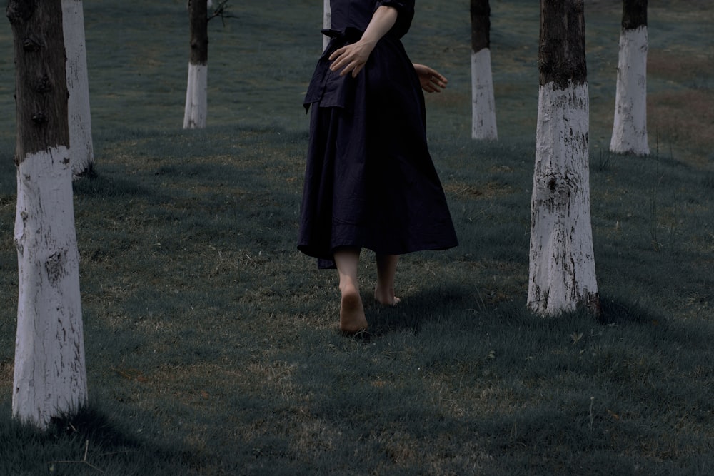 a woman is walking through a grove of trees