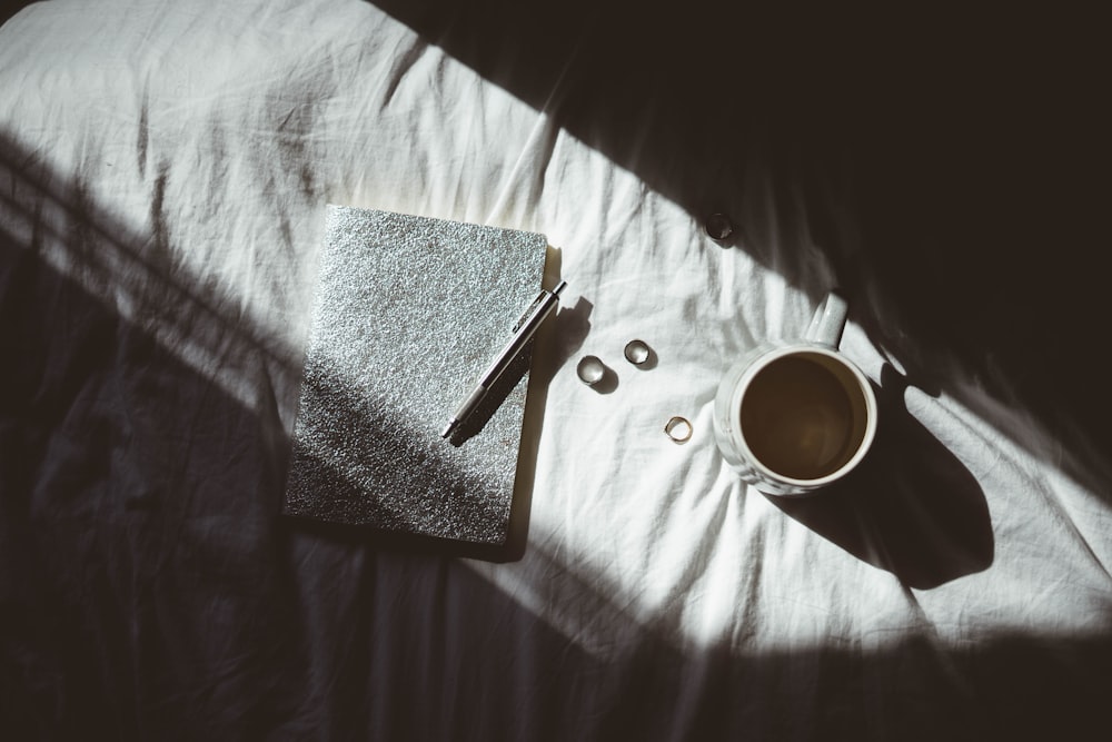 a cup of coffee and a book on a bed