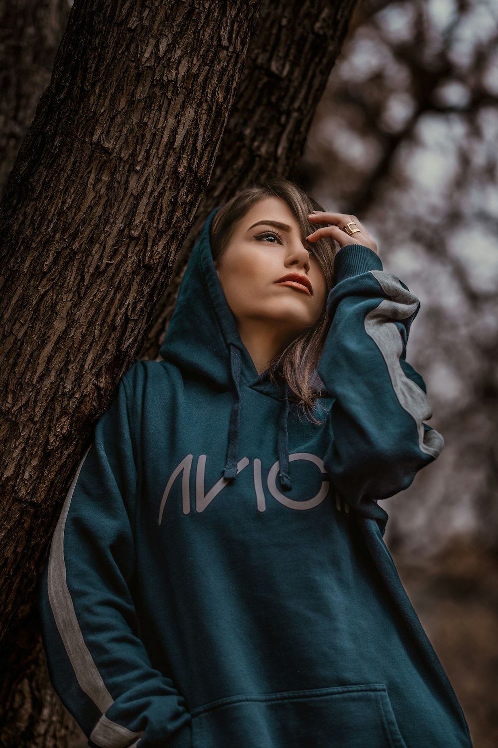 woman wearing black pullover hoodie leaning on tree