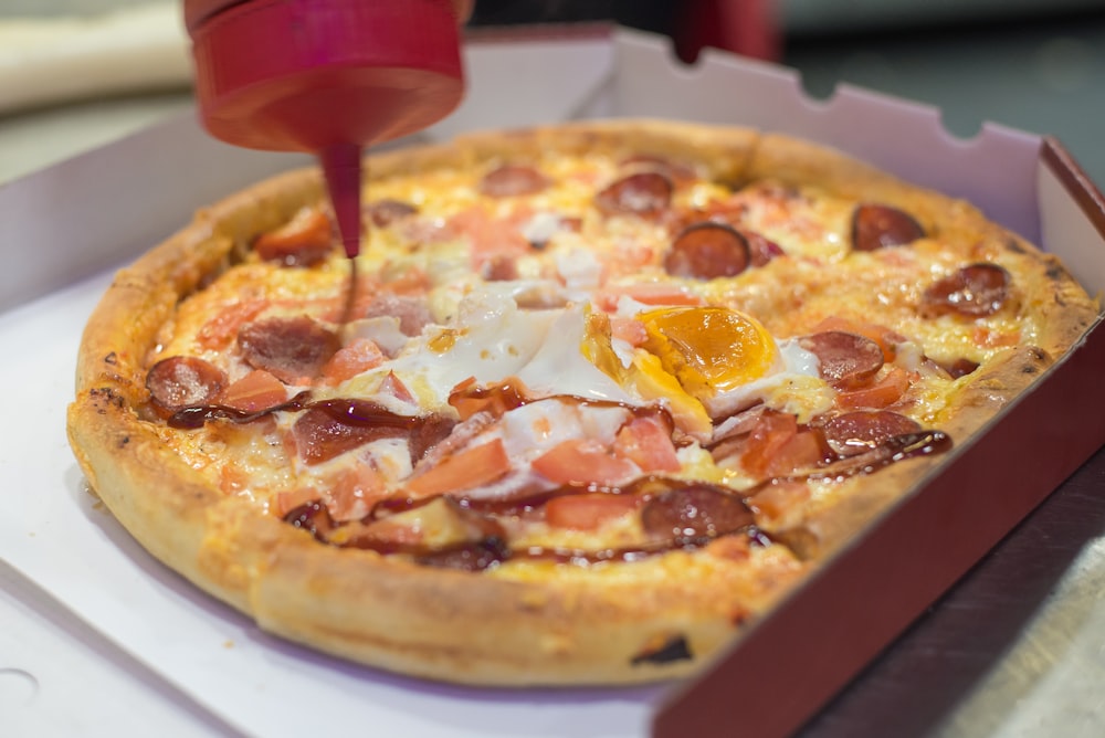 ketchup being poured on pizza