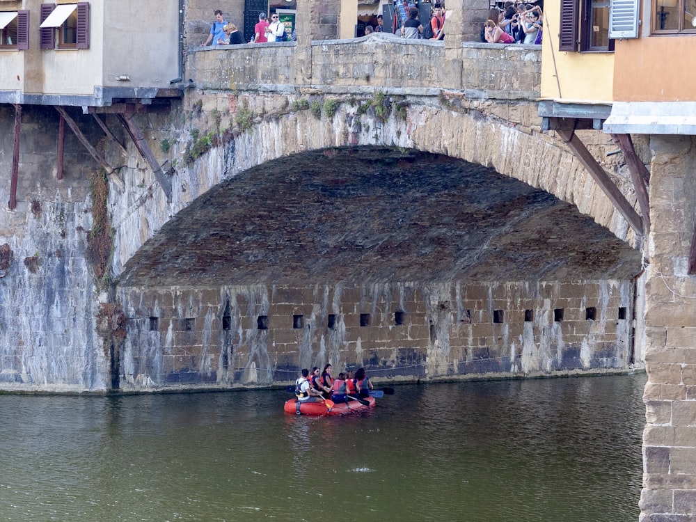 persons on boat underneath bridge