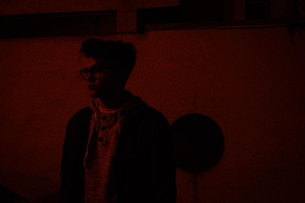 man in black jacket standing in front of wall