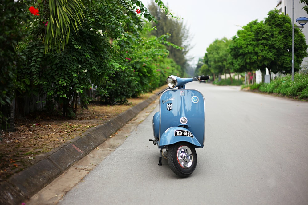 blue Vespa classic motor scooter parked at roadside