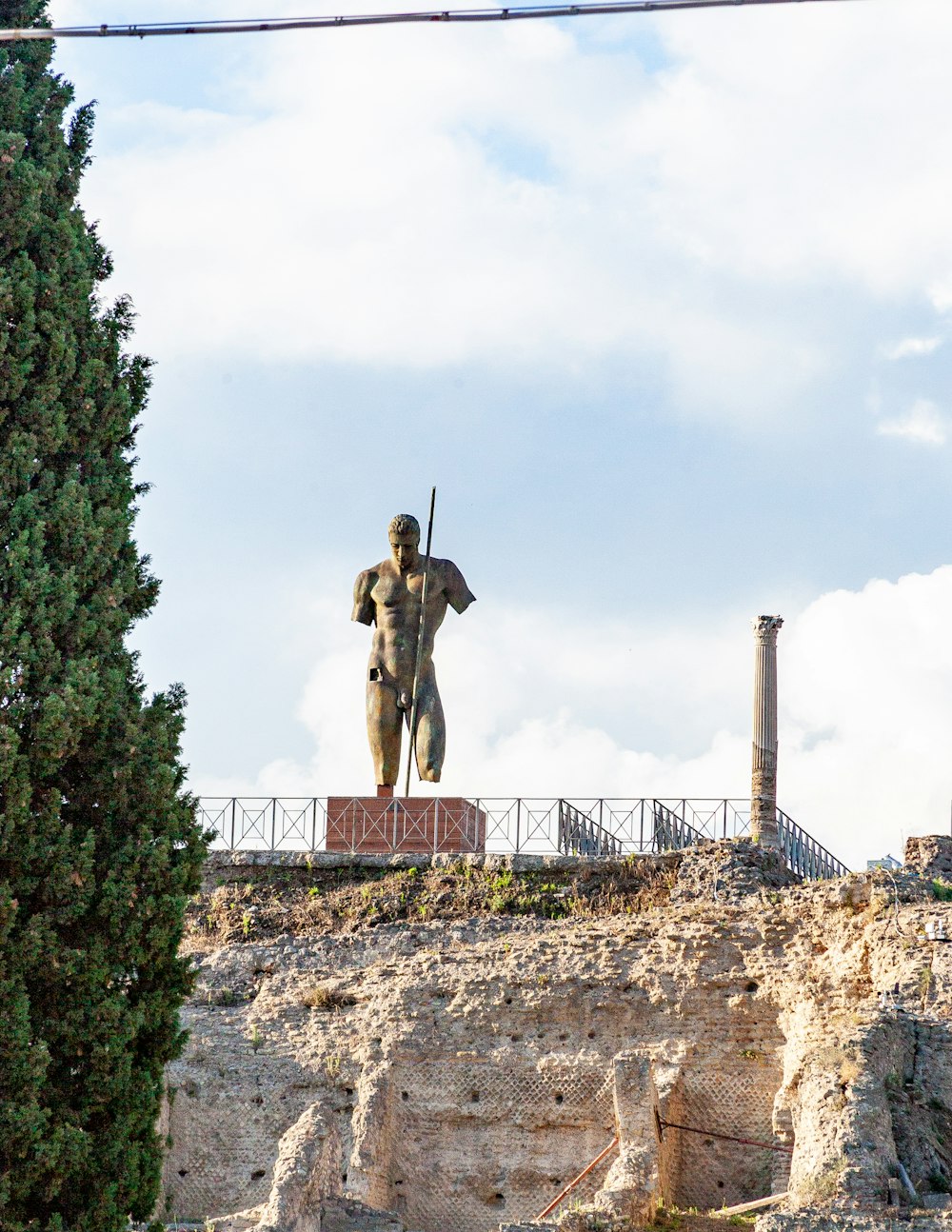 armless and one-legged standing man statue on top of mountain during day