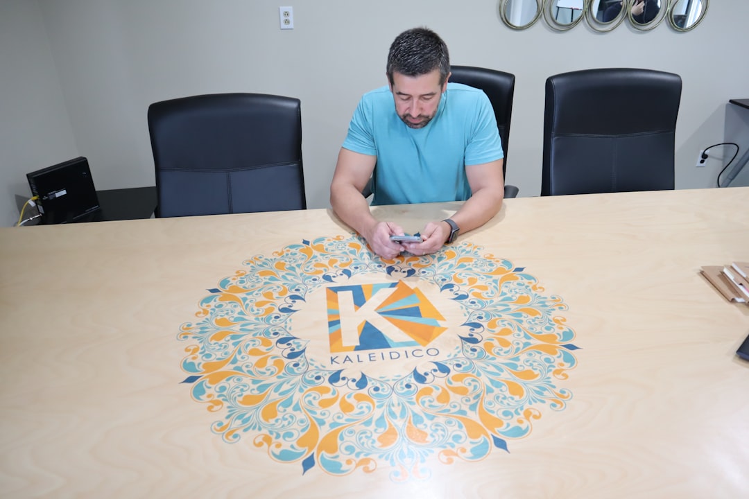 man sitting beside table using smartphone