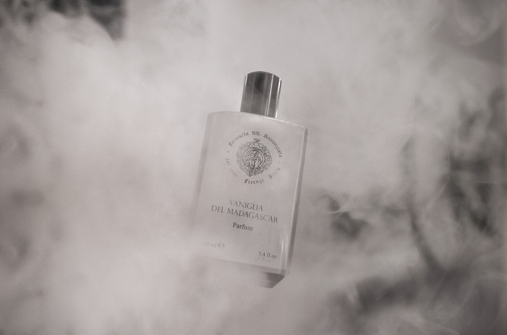 a bottle of cologne sitting on top of a cloud of smoke
