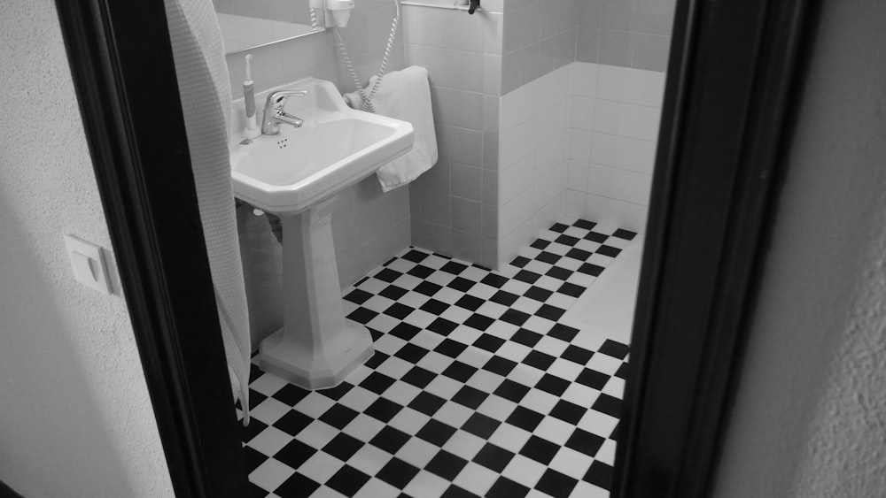 grayscale photo od white pedestal sink