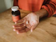 A person holding a capsule bottle labeled for health and wellness enhancers.