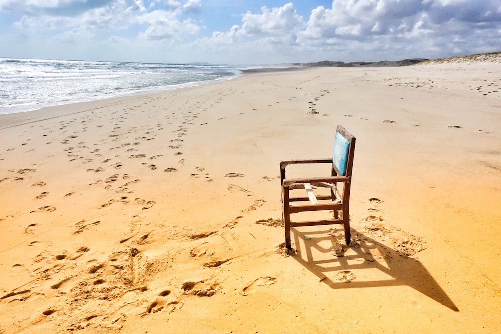 brown wooden armless chair near seashore viewing sea