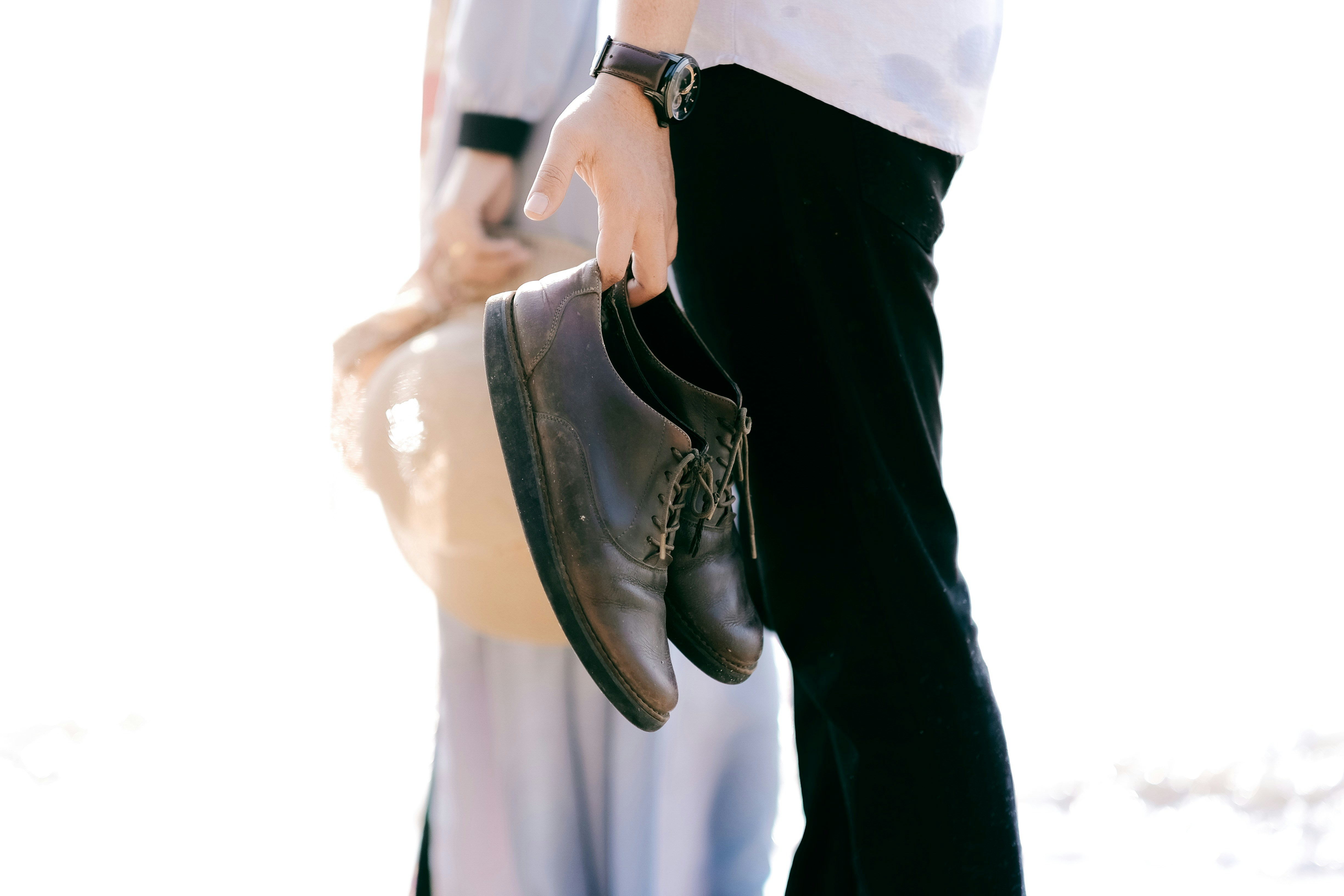 Person, die in der Nähe einer anderen Person geht, während sie braune Lederschuhe hält