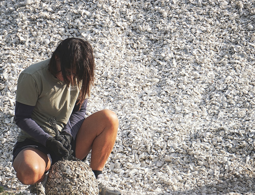woman in gray shirt sitting on gray rock