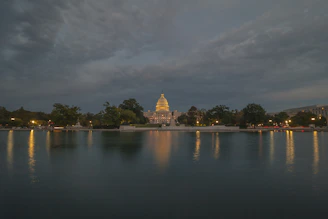 A dignified view of the Virginia State Capitol bathed in soft morning light, framed by historic oak trees.
