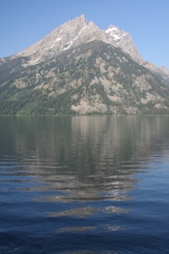 Towering granite peaks of Torres del Paine reflected in a crystal-clear glacial lake surrounded by lush greenery.