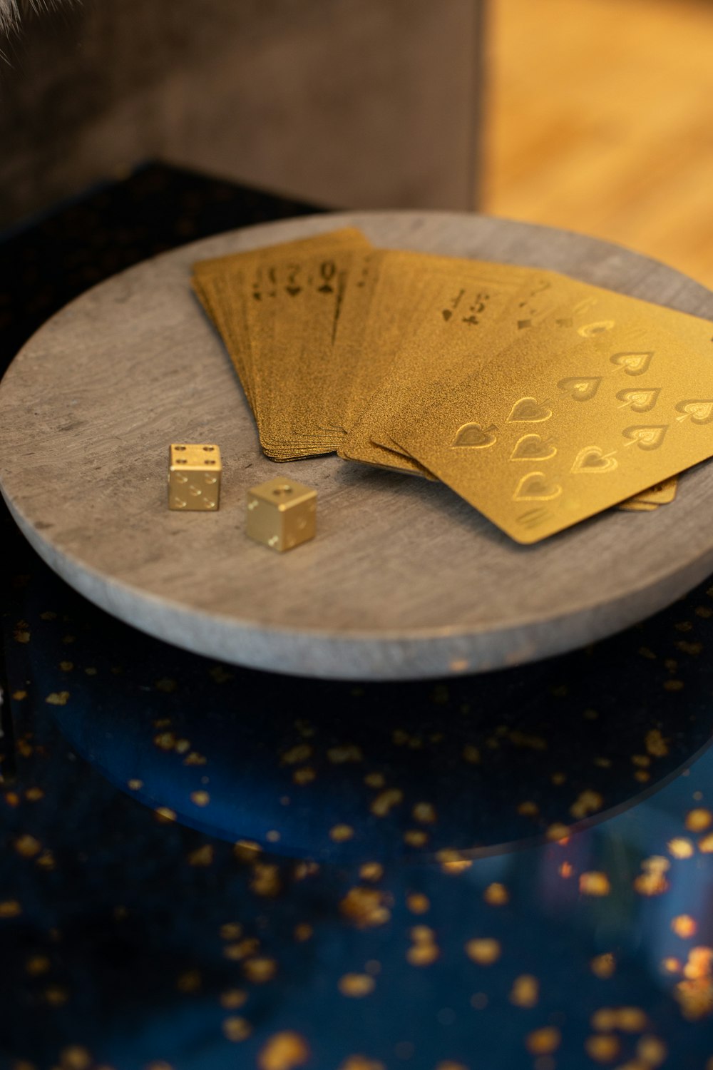 Cartas doradas y dos dados sobre plataforma redonda de madera