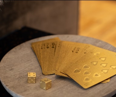 gold cards and two dices on round wooden platform