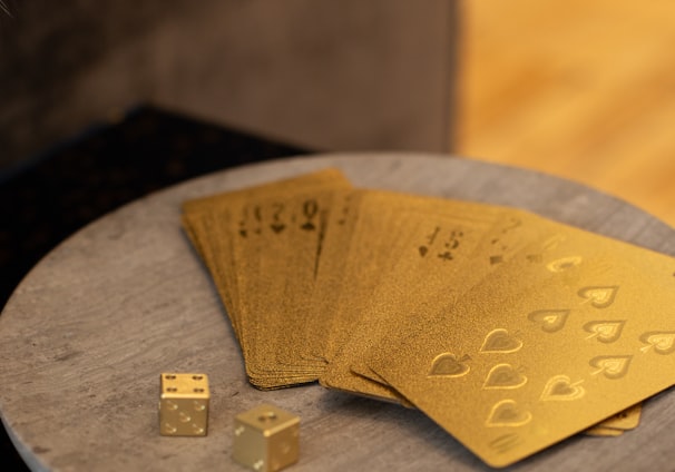gold cards and two dices on round wooden platform