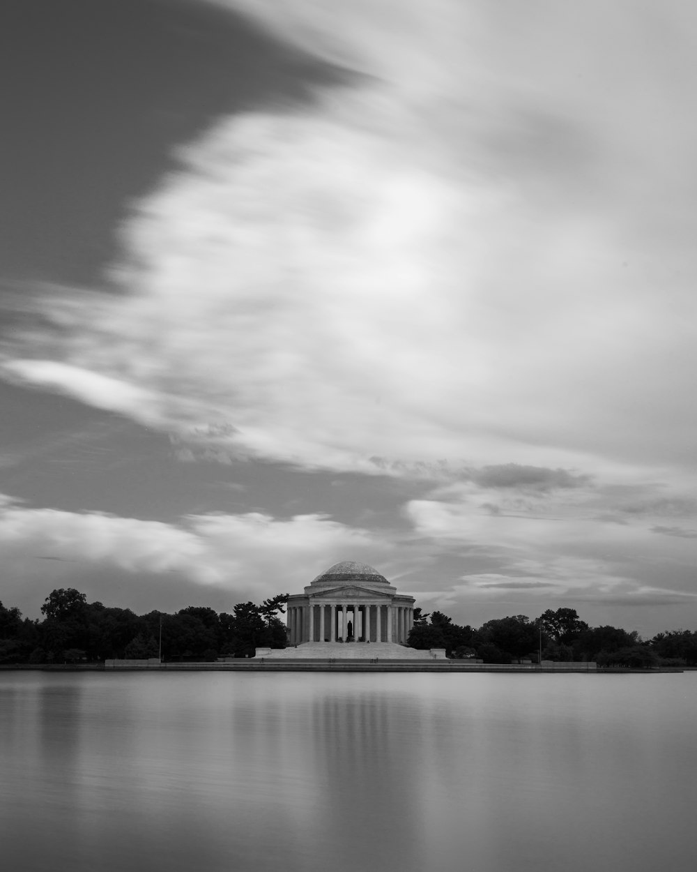 white building near trees and body of water