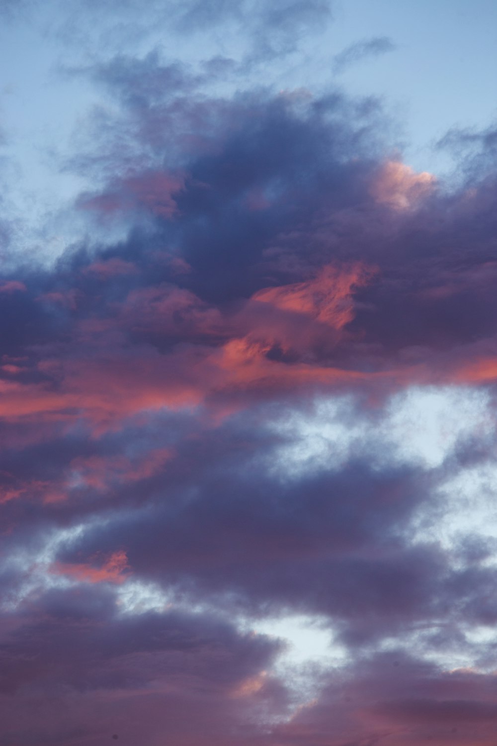 a plane flying through a cloudy sky at sunset