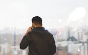 Close-up of a motivated professional speaking confidently on the phone with a city skyline in the background.