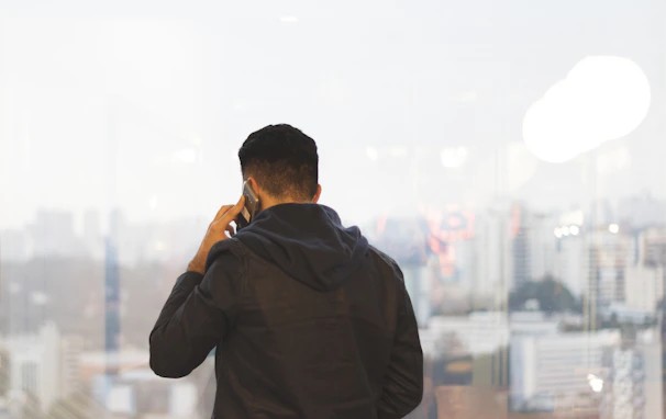 A consultant providing advice over the phone, with the Düsseldorf cityscape visible through the window.