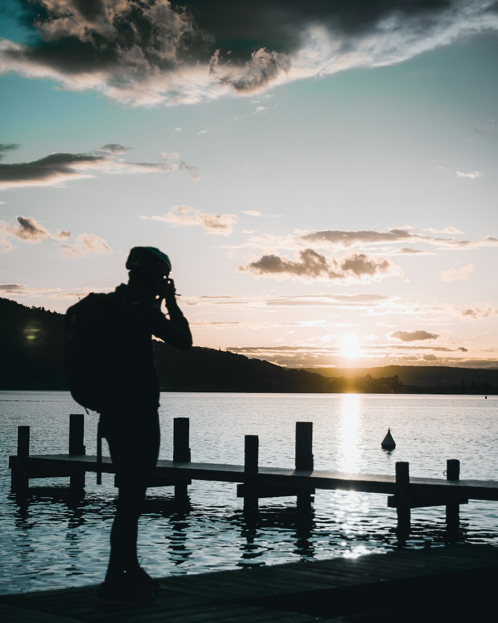 silhouette of person standing near dock during daytime