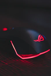A sleek gaming mouse glowing with RGB lights on a dark desk surface.
