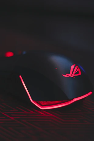 A futuristic gaming mouse with sharp angles and glowing red accents on a reflective surface.