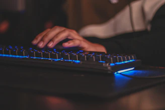 Close-up of hands typing on a laptop with electric blue lighting.
