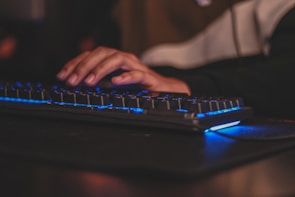Hands typing on a keyboard with a white desk and blue accent lighting.