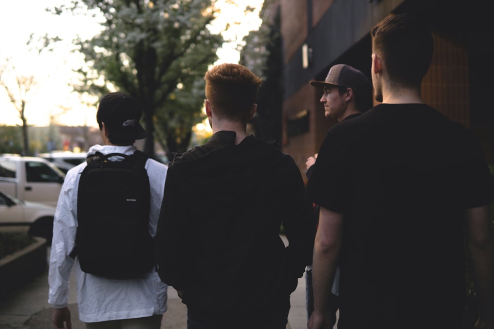 four men standing near cars