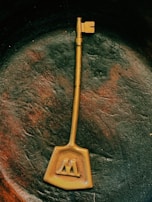 An elegant golden key resting on dark charcoal stone with subtle jungle textures.