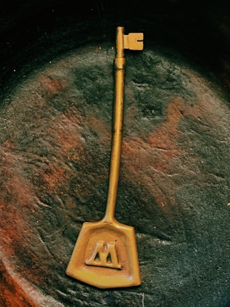 An elegant golden key resting on a textured black surface, hinting at hidden treasures and exclusive access.