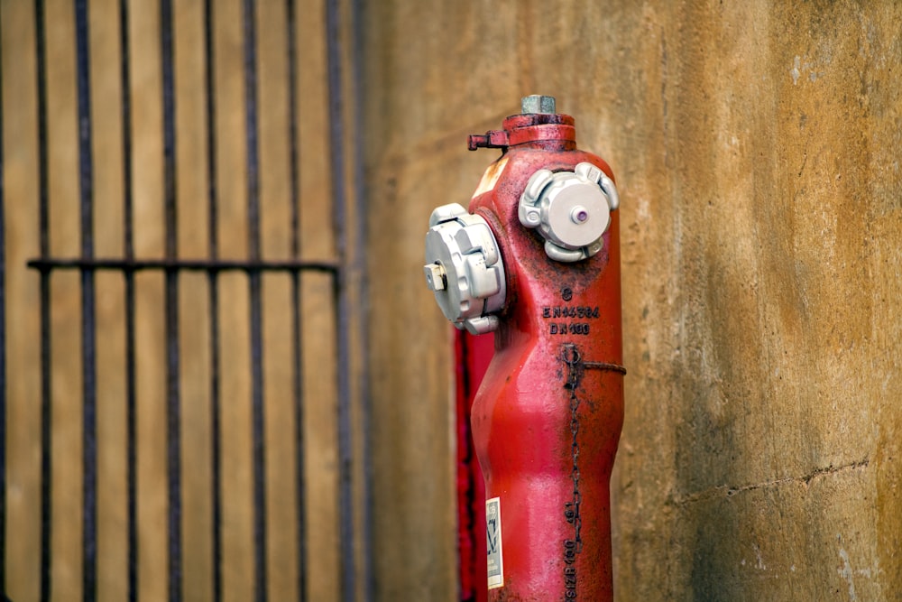 a red fire hydrant next to a wooden fence