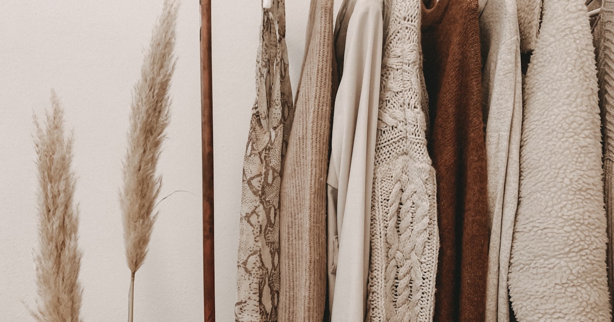 A curated clothing rack with neutral-toned knit garments in a minimalist boutique setting