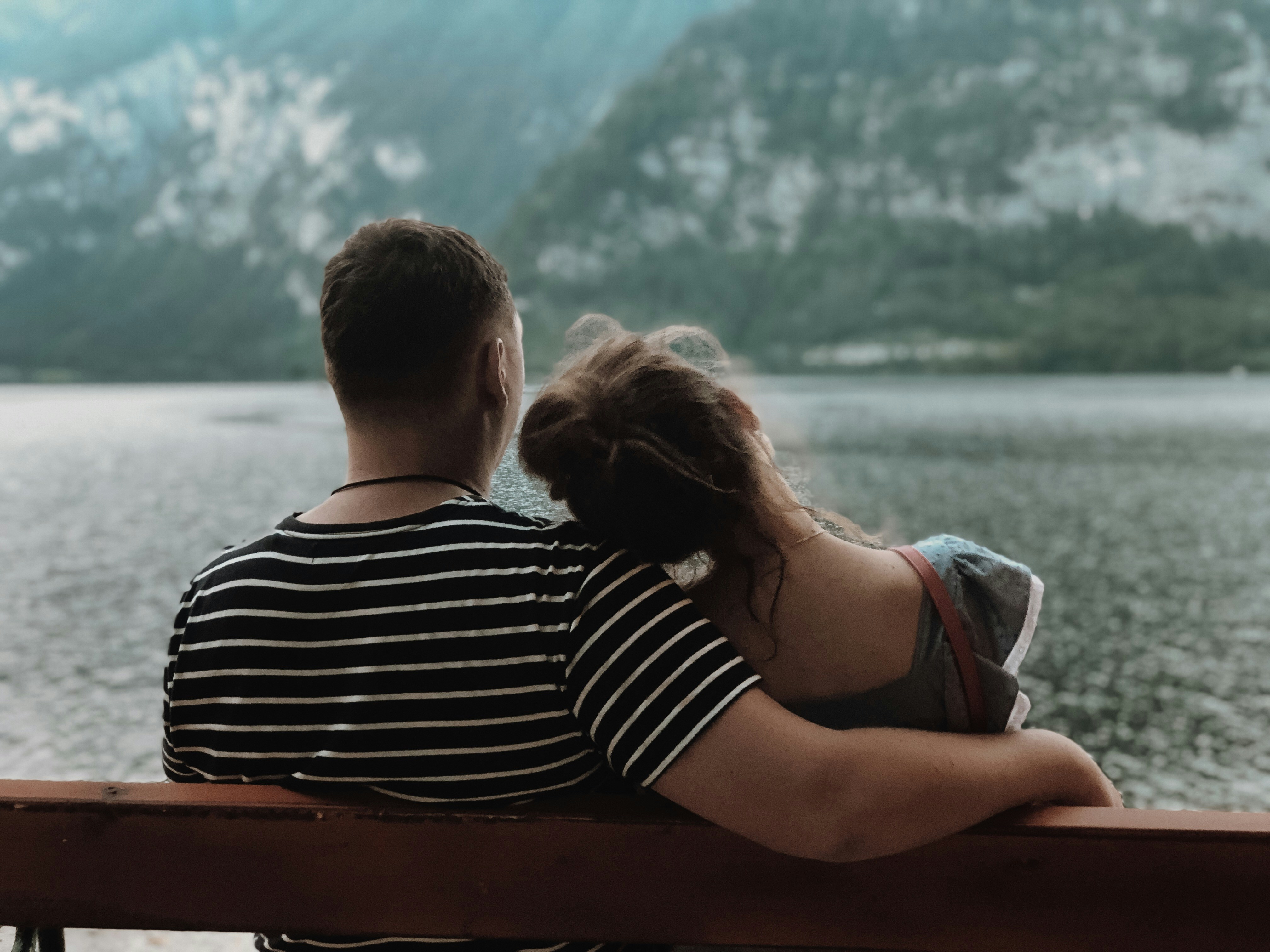 couple sitting on a bench looking at a sunset - build peace loving marriage