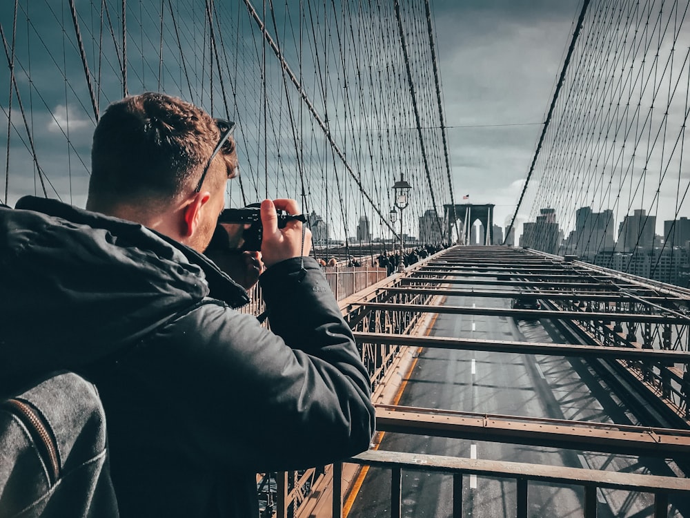 man taking photo on bridge top