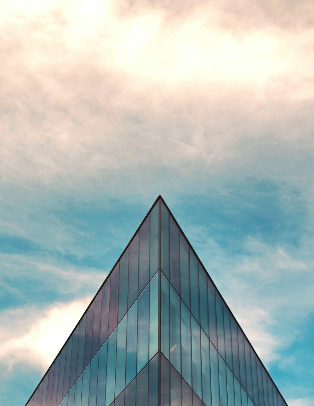 blue and gray glass walled building under white and blue skies