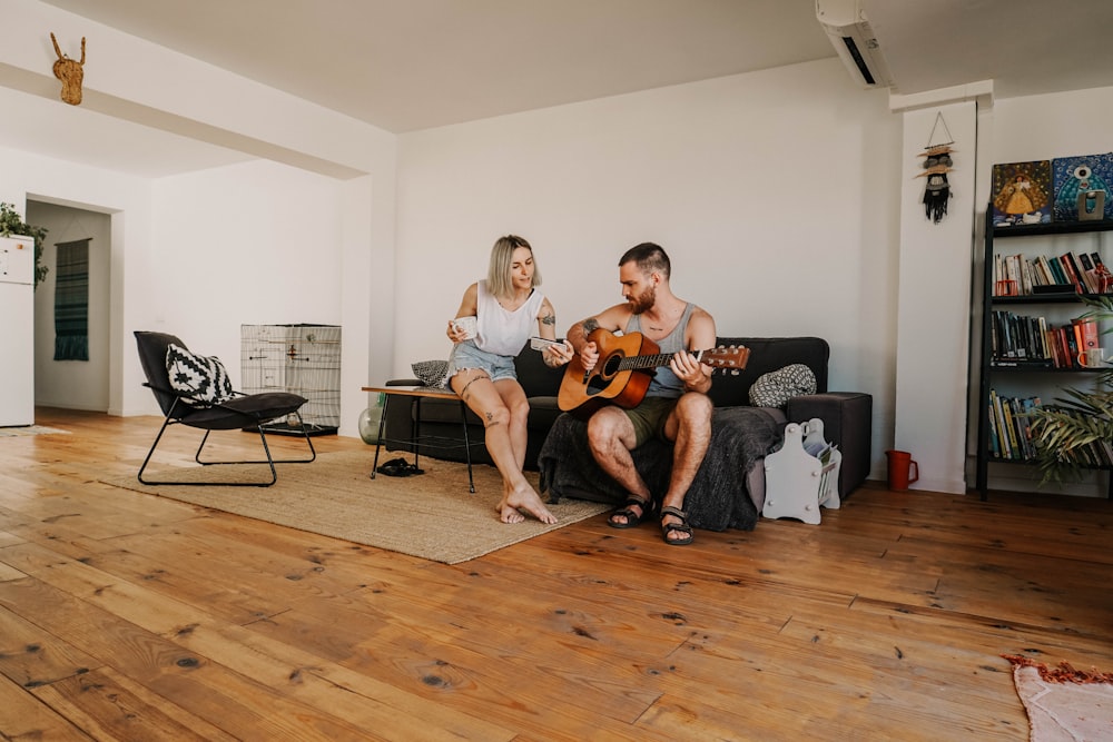 homem sentado e tocando violão perto da mulher na sala de estar