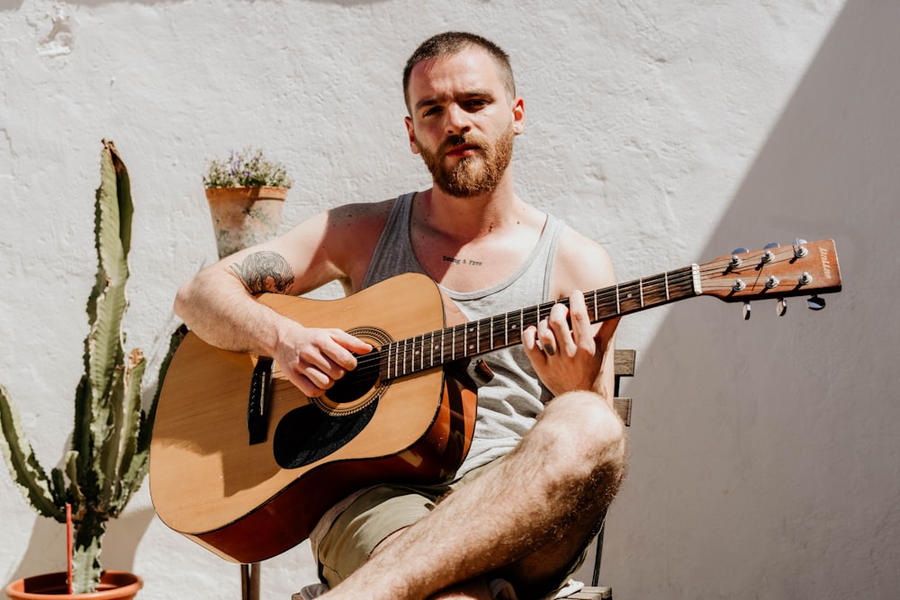 man sitting on chair playing guitar